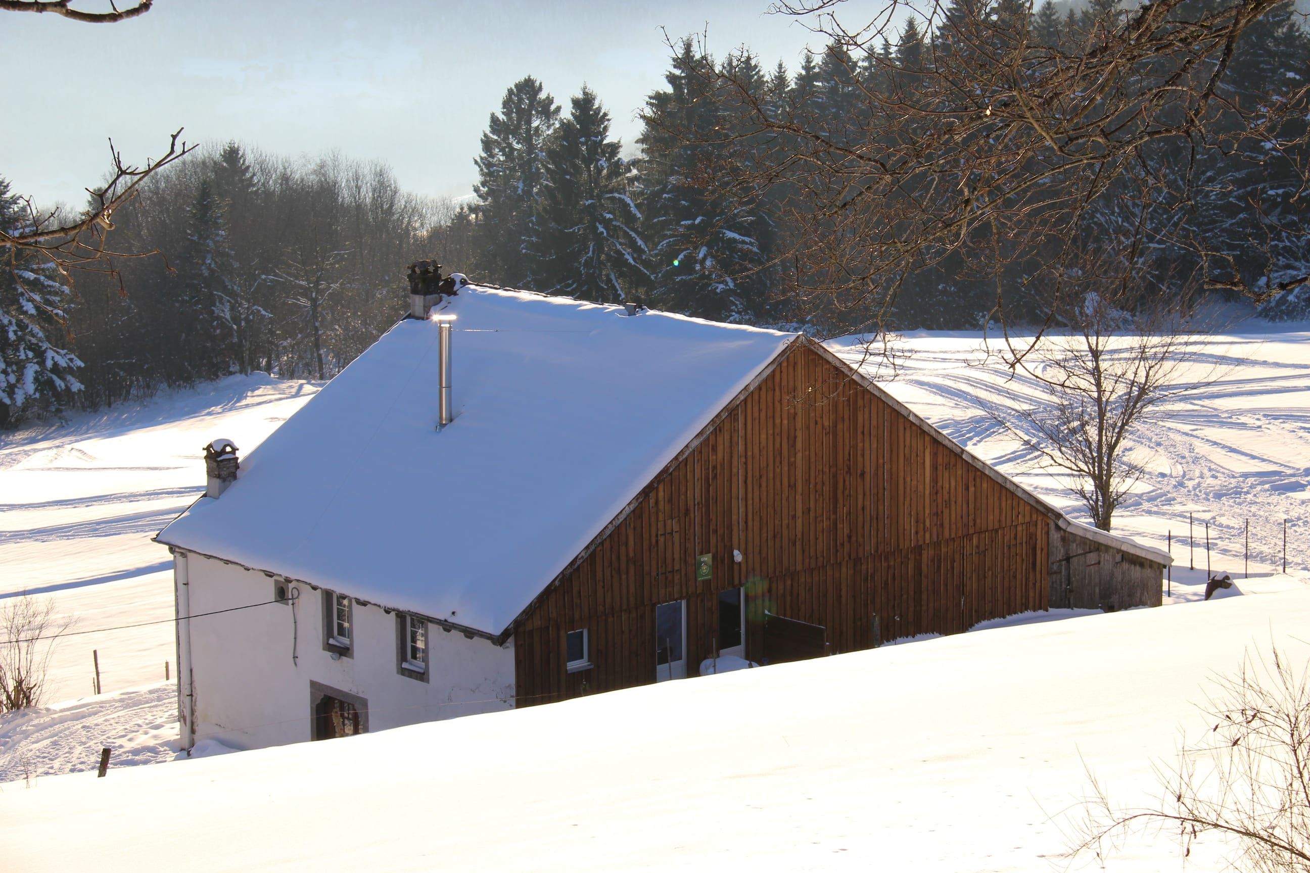 La ferme enneigée, façade blanche et grange en bois