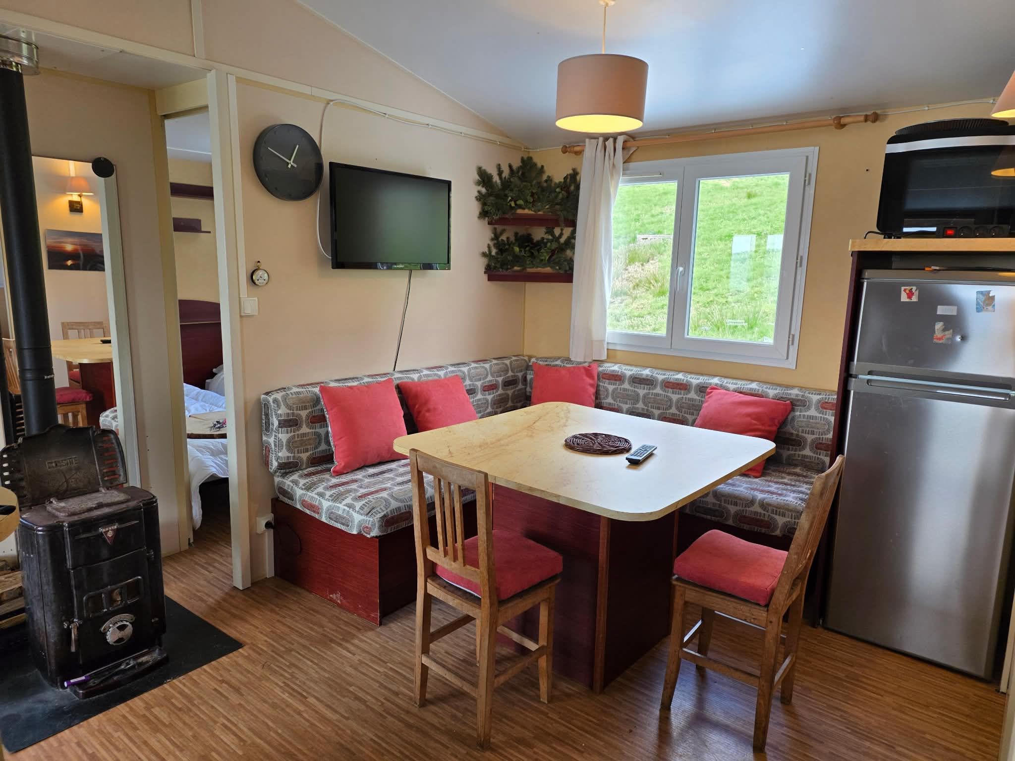 Le séjour de la Cabane : banquette, table, poêle et coin cuisine